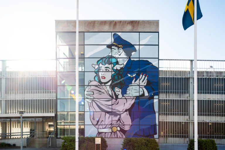 D*Face konstverk på ett av parkeringshusen vid Landvetter Flygplats. Målningen föreställer en kvinna och man i pop-art som håller om varandra.